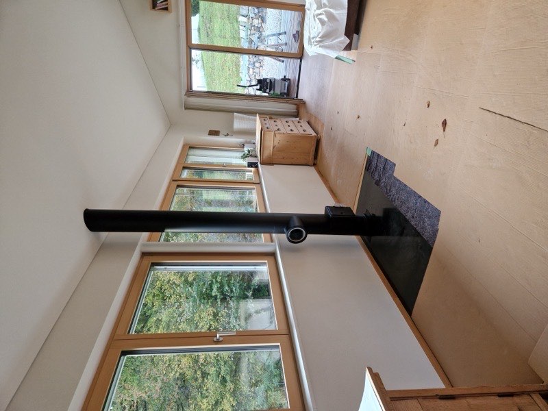 Schwarzes Rauchrohr in einem hellen Wohnraum, Arbeit von ALBÖ Kaminbau